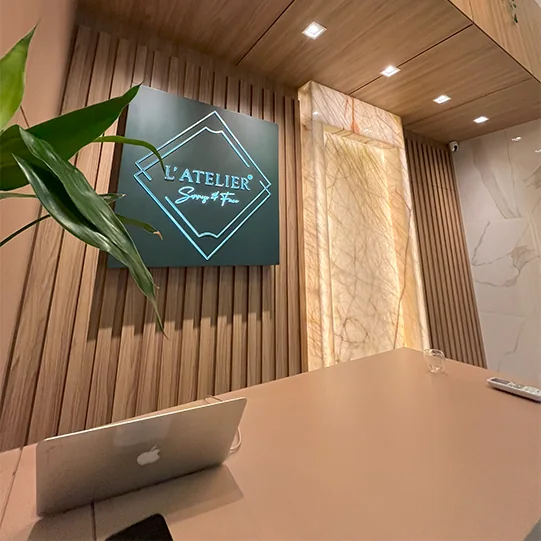 Recepção da clínica com letreiro L'ATELIER iluminado